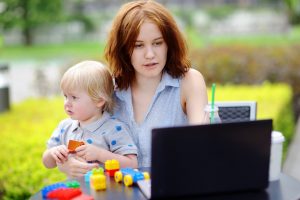 Young mother searching divorce attorney near me on her laptop and holding her sad toddler son