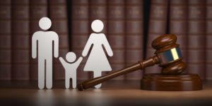 Paper man, child and woman holding hands next to gavel representing Family Law Attorneys Birmingham 